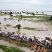 People walk through floodwaters near flooded farmlands after heavy rainfall in Hadeja, Nigeria, Sept 19, 2022.