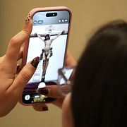 En ungdomsmedlem i Corpus Christi katolska kyrka, fotograferar en staty av den korsfäste Jesus inför långfredagsprocessionen måndagen den 23 mars 2026 i Miami, Florida.