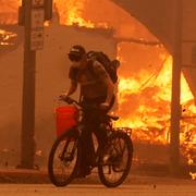 En cyklist passerar en brinnande byggnad i Pasadena i norra Los Angeles på onsdagen.