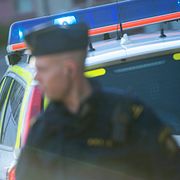 En polisman i yttre tjänst framför en polisbil. Arkivbild.