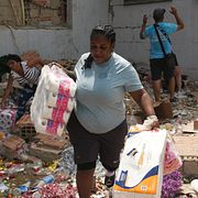 Människor bär ut varor från förstörda butiker i Catia La Mar, Venezuela den 25 juni 2026.