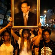 Tre kvinnor håller upp en tavla föreställande den nu avlidne kung Bhumibol Adulyadej utanför Siriraj-sjukhuset i Bangkok.