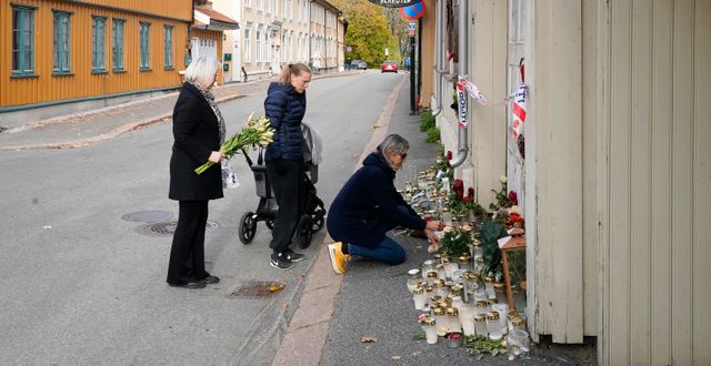 Människor lägger blommor vid en minnesplats i Kongsberg.  Terje Bendiksby / TT NYHETSBYRÅN