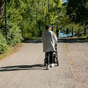 En kvinna med barnvagn promenerar längs Årstaviken på Södermalm i Stockholm.