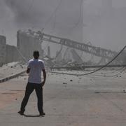 Palestinier ser på förödelsen när en byggnad i Gazaremsan kollapsar. 