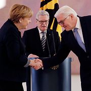 Frank-Walter Steinmeier skakar hand med Angela Merkel. I bakgrunden avgående presidenten Joachim Gauck.