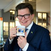 Talmannen Andreas Norlén med en kaffekopp prydd med texten ”Talmanspresidiet 2022–2026” och en bild på honom och de vice talmännen.