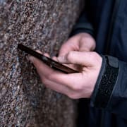 En ung kille med en mobiltelefon. Illustrationsbild. 