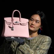 A Bonhams employee displays a Hermes: Rose Sakura Swift Leather Birkin 25 bag at the auction rooms in London, Monday, Feb. 26, 2024.