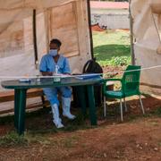 Sjukvårdspersonal i Uganda vid en skylt som informerar om symtom på ebola.