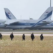 Polisen söker igenom ett fält på fredagen. Planen på bilden tillhör ett ryskt fraktbolag och har varit strandsatta på flygplatsen i flera år på grund av sanktioner som införts efter den ryska storskaliga invasionen av Ukraina.