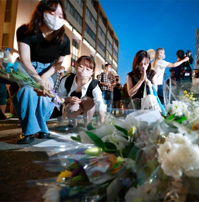 People pray at a makeshift memorial at the scene where the former Prime Minister Shinzo Abe was shot while delivering his speech to support the Liberal Democratic Party's candidate during an election campaign in Nara, Friday, July 8, 2022.  213646+0900 / AP