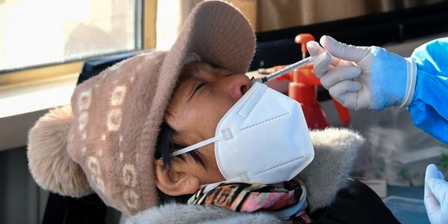 Kinesisk kvinna får en vaccindos i näsan, 17 december. Ren Chao / AP