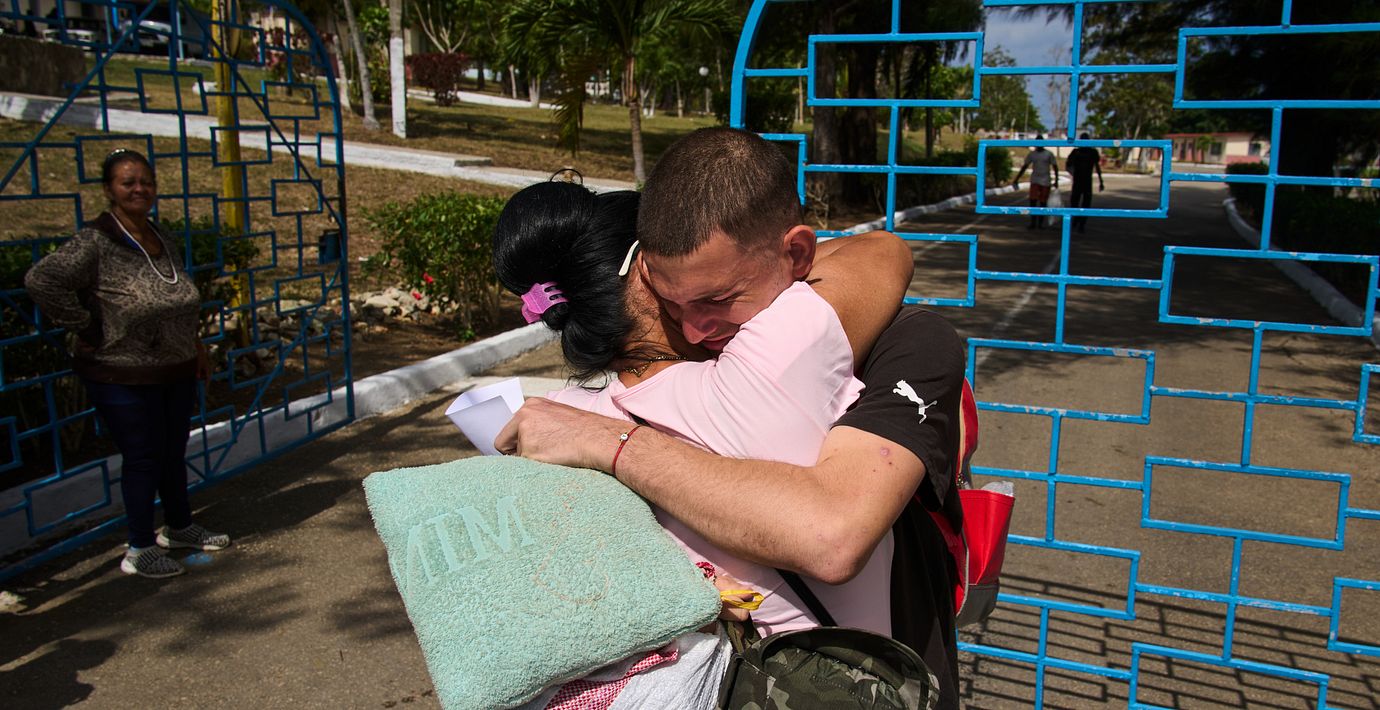 En man som blivit benådad kramar om sin familjemedlem utanför ett fängelse i Havanna.