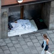 En hemlös person sover utanför en port i Stockholm.