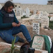 En journalist ber vid sin kollegas grav i Idlib. Fotografen Anas Alkharboutli, 32, som jobbade för tyska DPA dödades i ett flyganfall nära staden Hama.