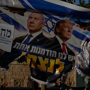 En kvinna och ett barn passerar en sönderriven valaffisch med Benjamin Netanyahu och Donald Trump i Jerusalem dagen efter det israeliska valet.