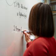Lärare skriver på whiteboard-tavla.