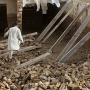 Människor inspekterar en skadad byggnad i regionen Kandahar i Afghanistan