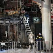 Brandmän framför den brandhärjade byggnaden i Hanoi.