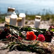 Blommor och ljus vid den badplats i Mölnlycke där en man i 45-årsåldern misshandlades till döds.