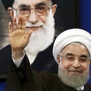 Irans president Hassan Rouhani vinkar under ett porträtt av Ayatollah Ali Khamenei.