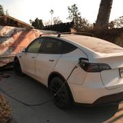 En Tesla står på laddning intill ett garage som brunnit ner i de svåra bränderna i Los Angeles.