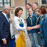 Kung Carl Gustaf och drottning Silvia hälsar på medlemmar ur Bergshamra scoutkår, under nationaldagsfirandet på Stockholms slott.