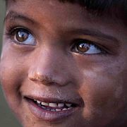 A nomadic child smiles as he rests on the banks of river Tawi on the outskirts of Jammu, Tuesday, India, Nov. 15, 2022. (AP Photo/Channi Anand)  JMU103