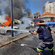 Räddningsarbetare släcker brinnande bilar efter en israelisk attack mot hamnstaden Sidon i södra Libanon den 10 juni.