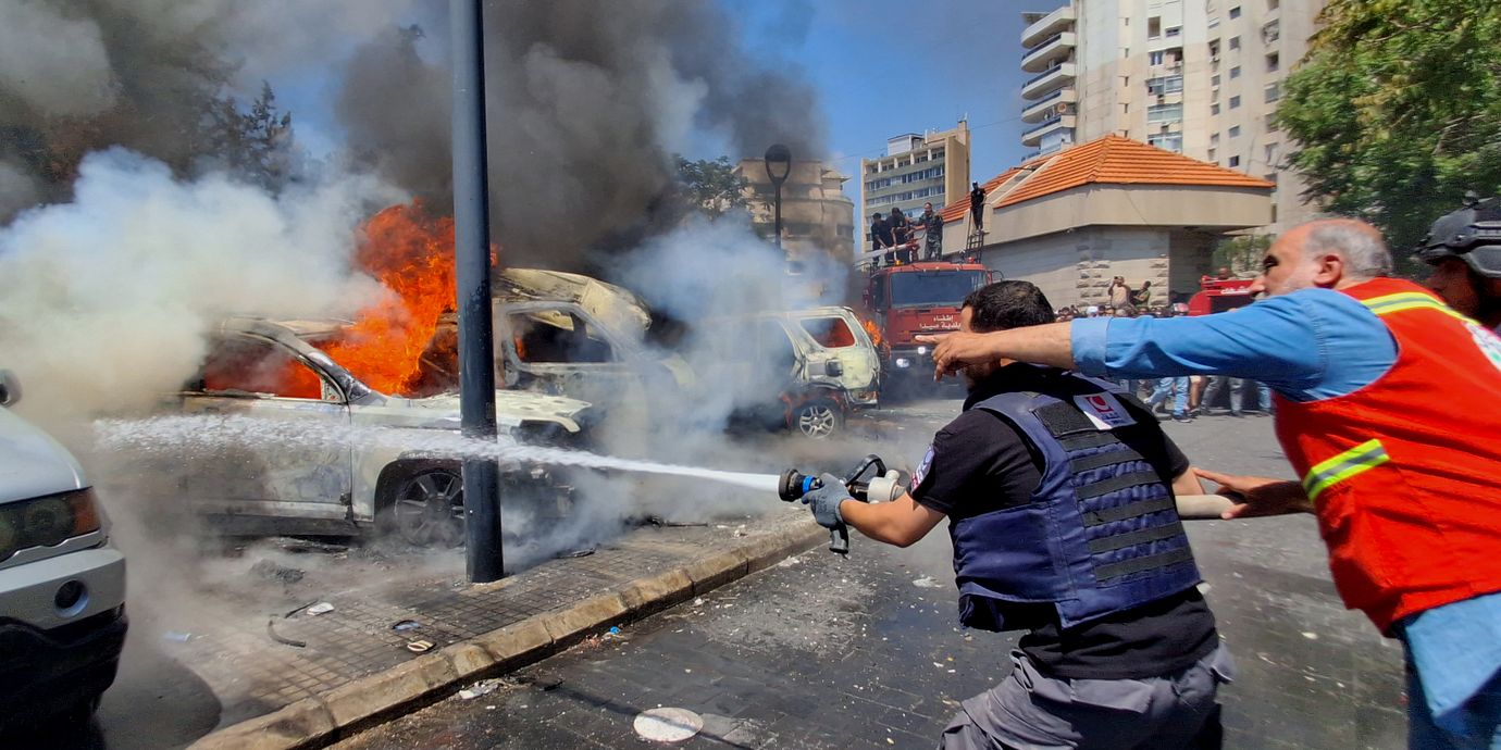 Räddningsarbetare släcker brinnande bilar efter en israelisk attack mot hamnstaden Sidon i södra Libanon den 10 juni.
