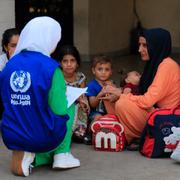 En UNRWA-medarbetare pratar med en palestinsk familj på ett flyktingläger. 