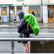En person med ryggsäck och regnjacka i regnet vid Slussen i Stockholm, illustrationsbild (2023).