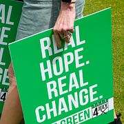 En medlem i De gröna bär valaffischer med texten ”Verkligt hopp. Verklig förändring” inför valet 2024.