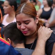 Människor står utanför en skola i Caracas en dryg vecka efter att den rasade ihop i skalven.