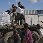Palestinier hämtar mjöl från en lastbil från World Food Programme i rörelse i slutet av förra året. 