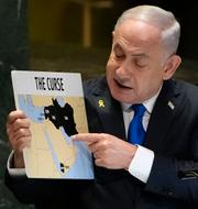 Benjamin Netanyahu håller upp en skylt som pekar ut flera länder i Mellanöstern som en ”förbannelse” under sitt anförande i dag. 