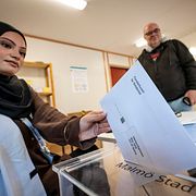 Fönsterkuvert med valsedlar läggs i valurnan vid förtidsröstning.