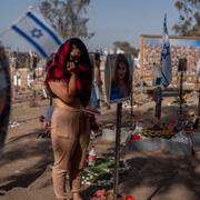 En kvinna vid ett porträtt av ett av terrordådets offer på platsen för musikfestivalen Nova som Hamas attackerade.
