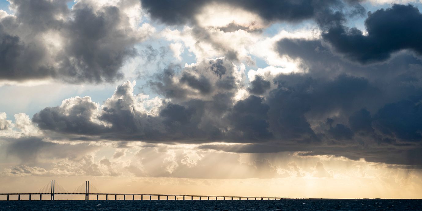 Arkivbild: Mörka moln med regn tornar upp sig över Öresundsbron medan solen är på väg ner i september 2018.