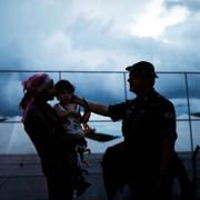 En brasiliansk militär talar med en kvinna och barn på venezolanska gränsen.