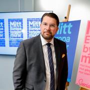 SD-ledaren Jimmie Åkesson bredvid en av partiets valaffischer.