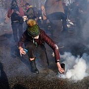 En demonstrant försöker neutralisera en tårgasgranat som skjutits av federala agenter under protesterna efter skjutningen av Renee Good i januari i år.