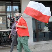 Människor i ansiktsmasker bär på en polsk flagga i Warszawa, Polen. 