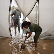 Sjuåriga Saja Fayyad försöker få ut vattnet ur familjens översvämmade tält i ett flyktingläger i Deir al-Balah, Gaza, den 25 november 2025.