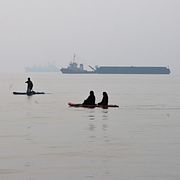 Människor paddlar på sup-brädor i Hormuzsundet utanför Bandar Abbas i Iran. I bakgrunden ligger handelsfartyg för ankar. Bilden är tagen den 6 oktober.