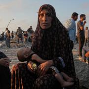 Somoud Wahdan har sitt barn i famnen när hon väntar på att lastbilar med nödhjälp ska anlända till Gaza, 25 juli.