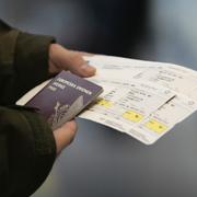 En person håller ett pass och resehandlingar. 