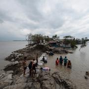 Lokalbor arbetar med att laga en trasig damm i staden Burigoalini i Bangladesh under stormens framfart.