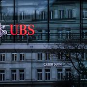 A traffic light signals green in front of the logos of the Swiss banks Credit Suisse and UBS in Zurich, Switzerland, Sunday March 19, 2023. (Michael Buholzer/Keystone via AP)  TH805